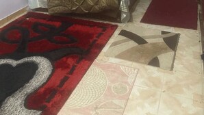 A bedroom with a bed, a nightstand, a red rug, and a patterned rug on the floor.