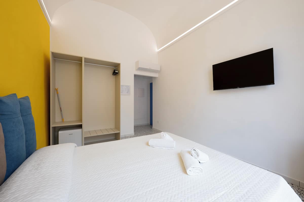 Una habitación de hotel con cama, armario, televisión de pantalla plana y puerta al baño.
