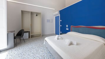A hotel room with a bed, a desk, a chair, a wardrobe, and a bathroom.
