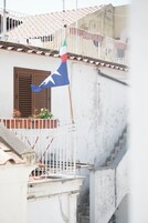 Un edificio con balcón, una bandera y una escalera.