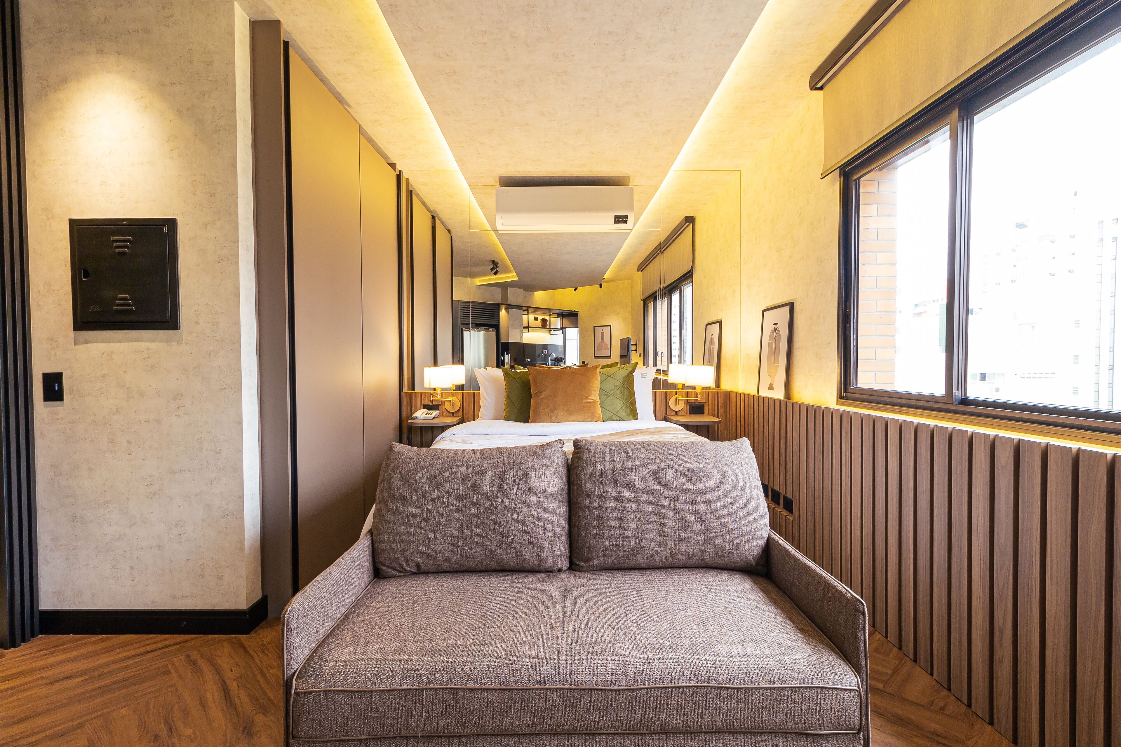 Ein Hotelgang mit Schlafsofa, Holzboden, Heizkörper und Fenster mit Blick auf Gebäude.