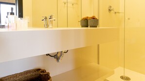 Un baño moderno con un espejo grande, cabina de ducha de vidrio y lavamanos blanco.