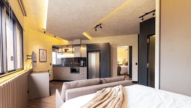 Una habitación de hotel con cama, sofá, kitchenette y baño.