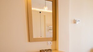 A small bathroom with a wooden vanity, a mirror, and a round stool. - Ostria Caldera Studio 2 (Thira - Santorini)