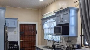 Una cucina compatta con forno a incasso, microonde e lavello. È presente un'area pranzo con tavolo apparecchiato per quattro persone.