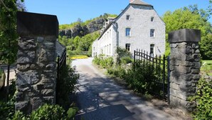 A stone building with a traditional architectural style, a paved driveway, and a stone gate.