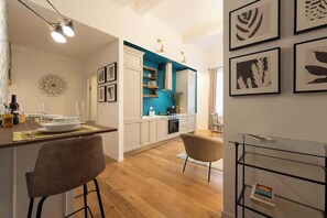 A modern kitchen with white cabinets, a blue accent wall, and a dining area with a bar.