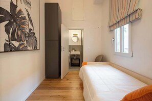 Une chambre à coucher comprenant un lit, une armoire, une salle de bain avec un lavabo et un miroir, et une fenêtre avec des rideaux.