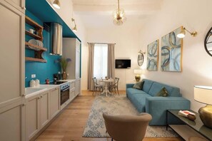 Un salon moderne avec un canapé bleu, un coin repas et une cuisine aux murs de couleur turquoise.