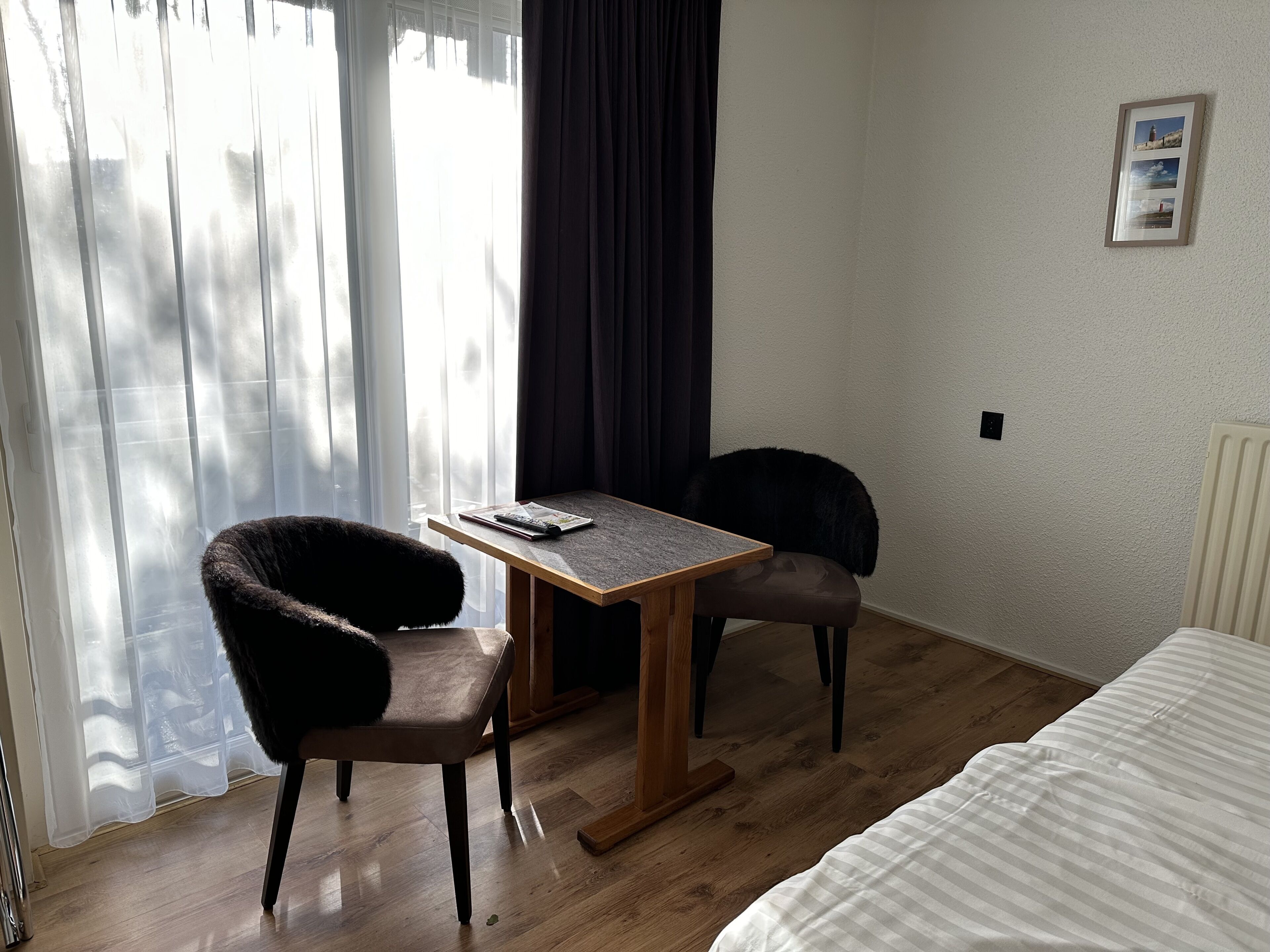 A small, tidy room with a bed, a table, and two chairs.