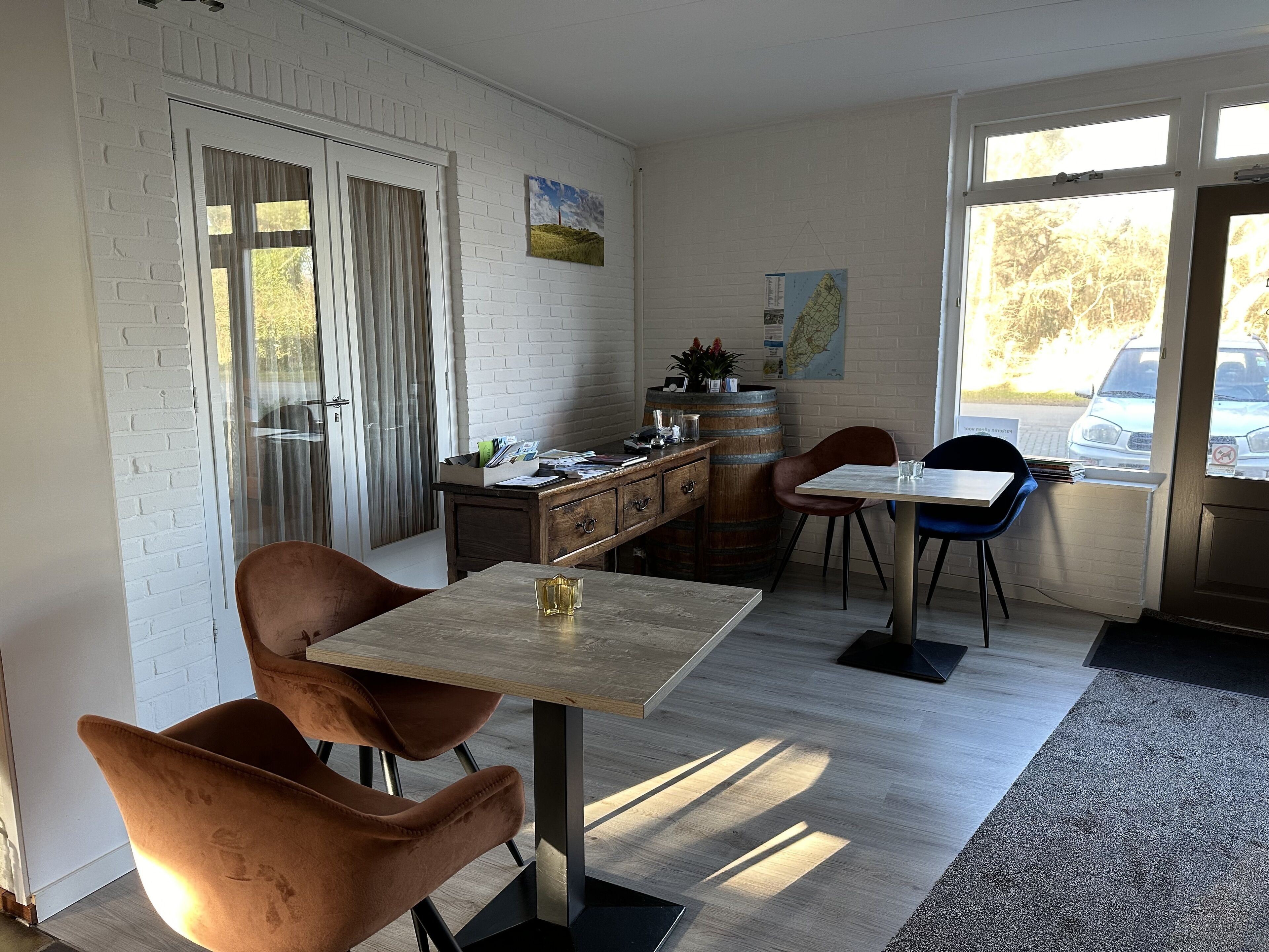 A dining area with a table and chairs, a wooden cabinet, and a window with a view of a car outside.