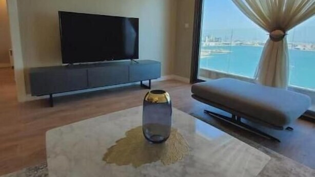 A modern living room with a flat-screen TV, a sofa, and a coffee table. - A Luxurious Sea View 1 Bedroom Apartment (Al HIDD)