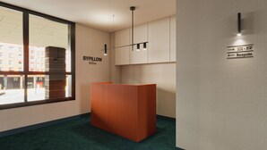 A reception area with a wooden reception desk, a wall-mounted sign indicating room numbers and reception, and a large window offering a view of the outside. - BYPILLOW Bilbo (Bilbao)