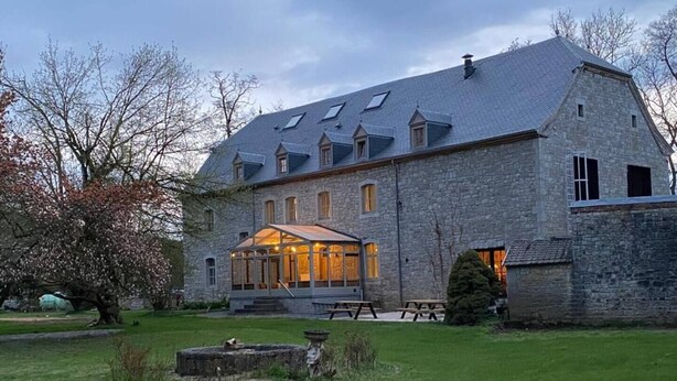 A stone building with a large glass conservatory, outdoor seating, and a well-maintained lawn. - La Tannerie De Durbuy - 28 Personen (Durbuy)