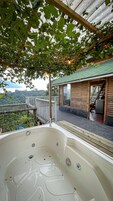 Una bañera de hidromasaje con una terraza de madera y vistas al paisaje circundante.