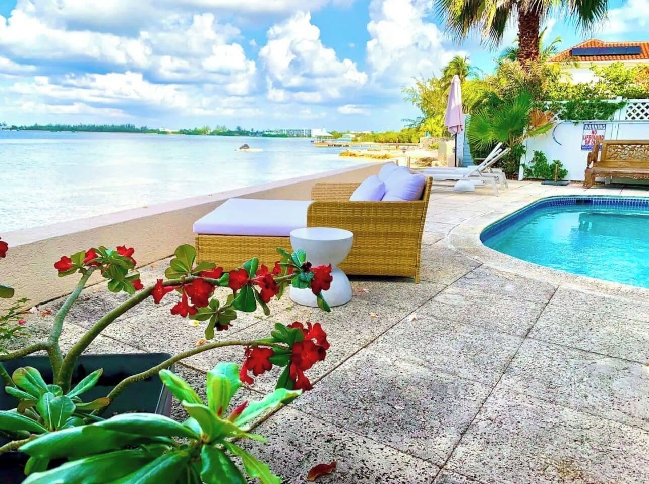 A poolside area with a lounge chair, a small table, and a sign warning about the pool.