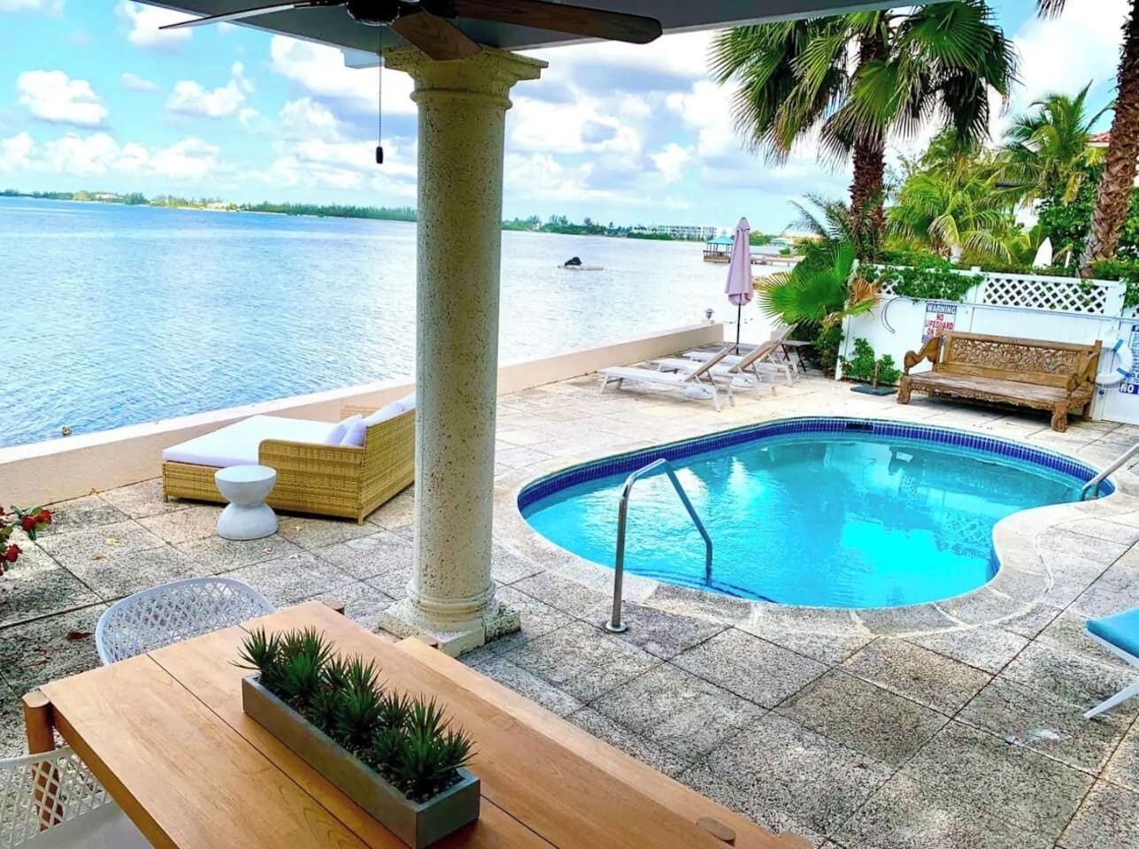 A pool area with a lounge chair, a bench, and a table.