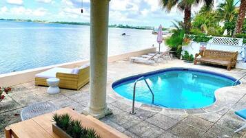 A pool area with a lounge chair, a bench, and a table.