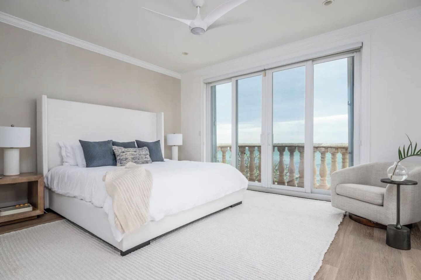 A bedroom with a large bed, a nightstand, a chair, and a view of the outdoors through a sliding glass door.