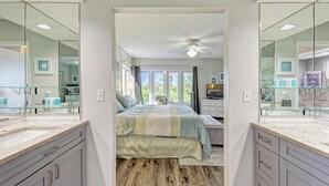 A bedroom with a large bed, a ceiling fan, and a view of the outdoors through a window. - Longboat Key Cedars Beach House-pet Friendly-2 Minute To The Beach (Longboat Key)