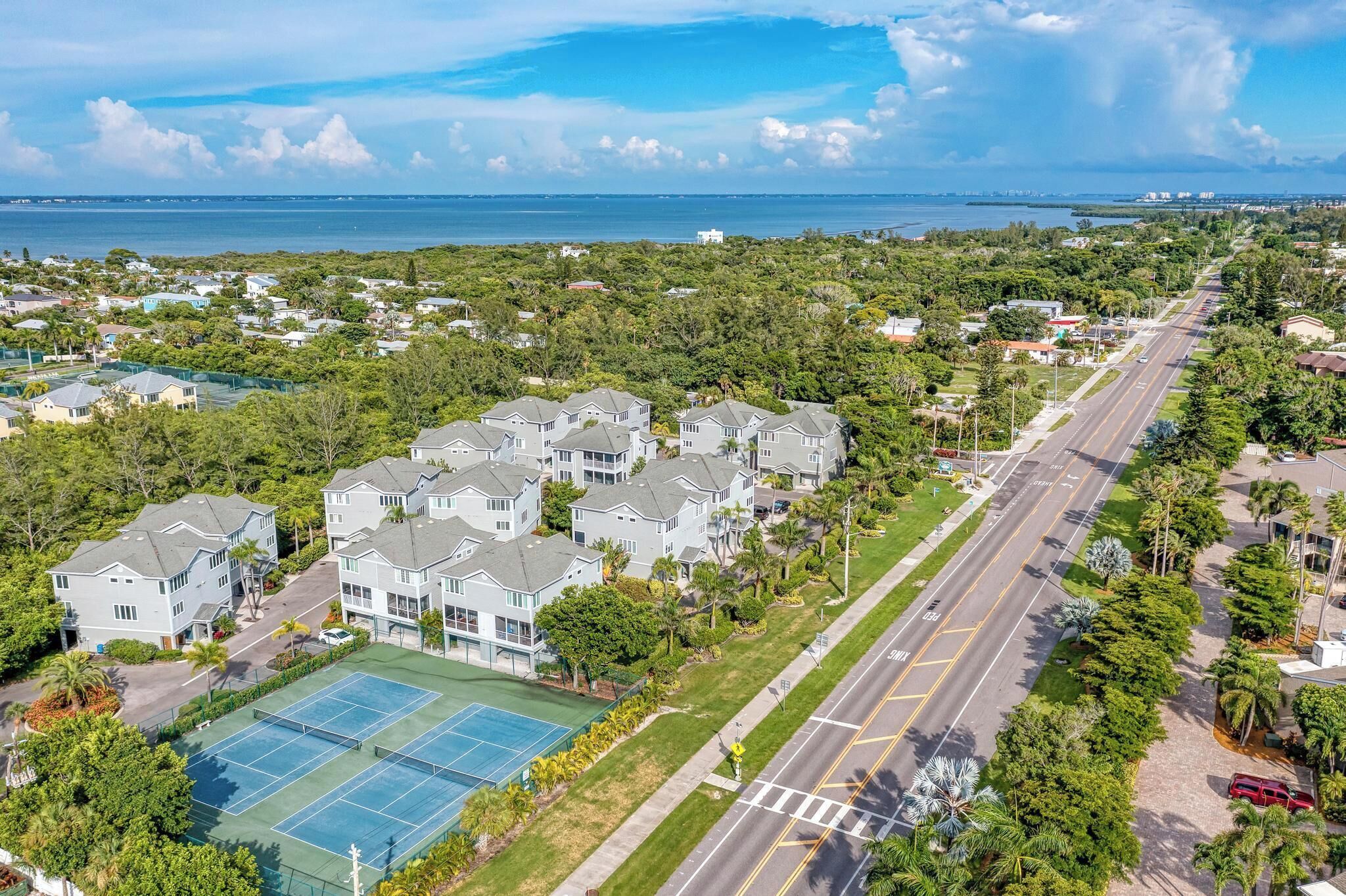 Zona residencial amb una pista de tennis, un carrer i vista a l'oceà.