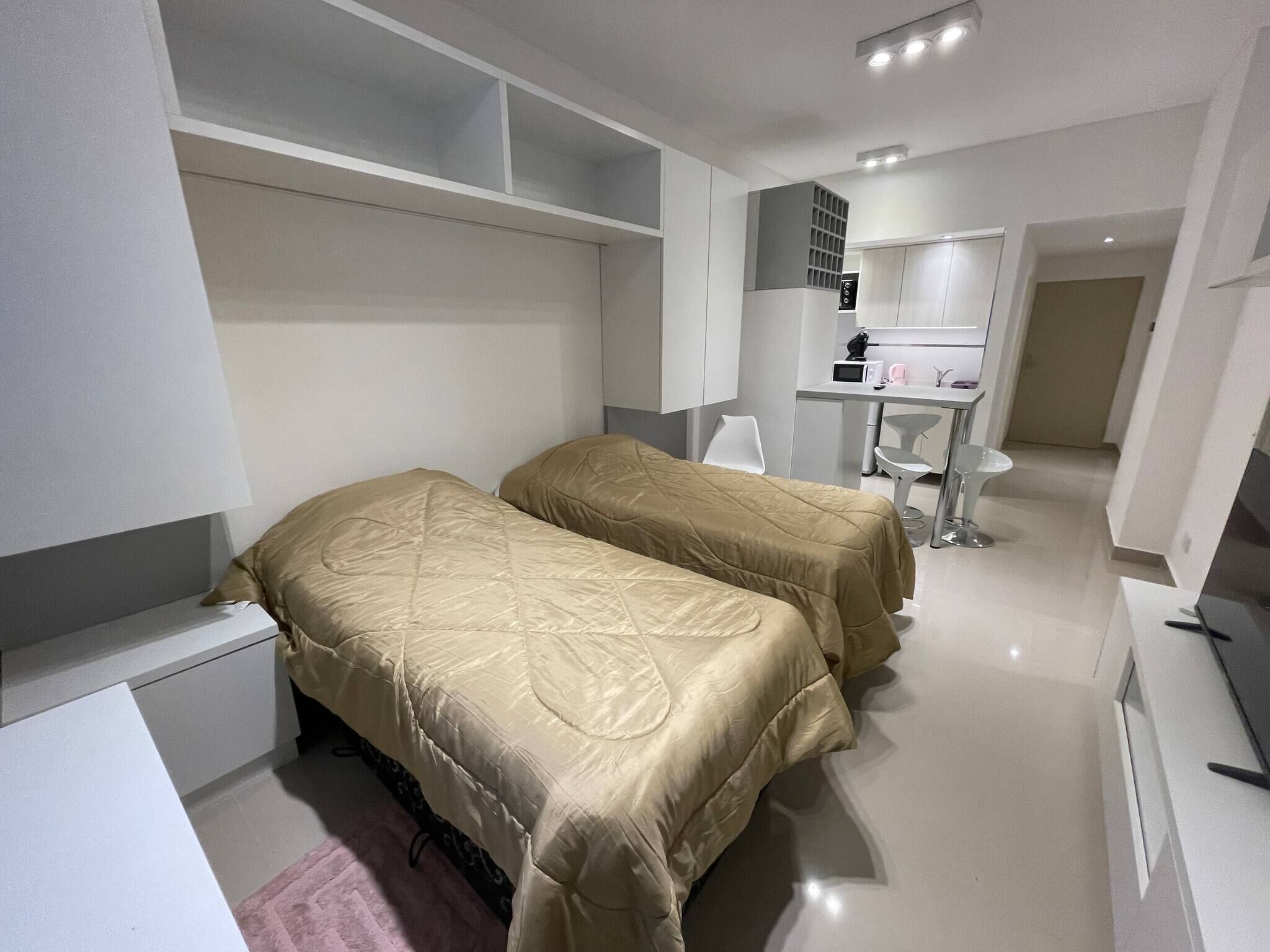 Ein modernes Hotelzimmer mit zwei Betten, einem Schreibtisch und einer Küchenzeile.