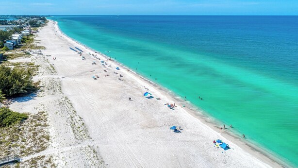 A beach with clear turquoise waters, a sandy shore, and a few umbrellas and beach chairs. - Bradenton Beach Club Bliss-2 Bedroom-2 Bathroom Condo-2 Pools-hottub-private Beach Access (Bradenton Beach)
