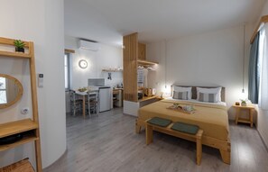 Une chambre d’hôtel moderne avec un lit en bois, un bureau et une kitchenette.