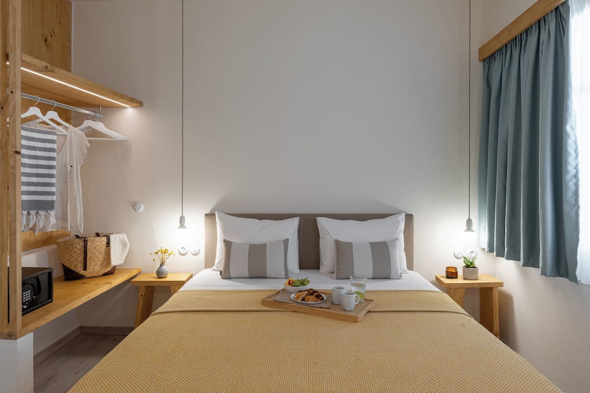Une chambre bien rangée, avec un lit, des tables de chevet, une armoire et une fenêtre avec des rideaux.