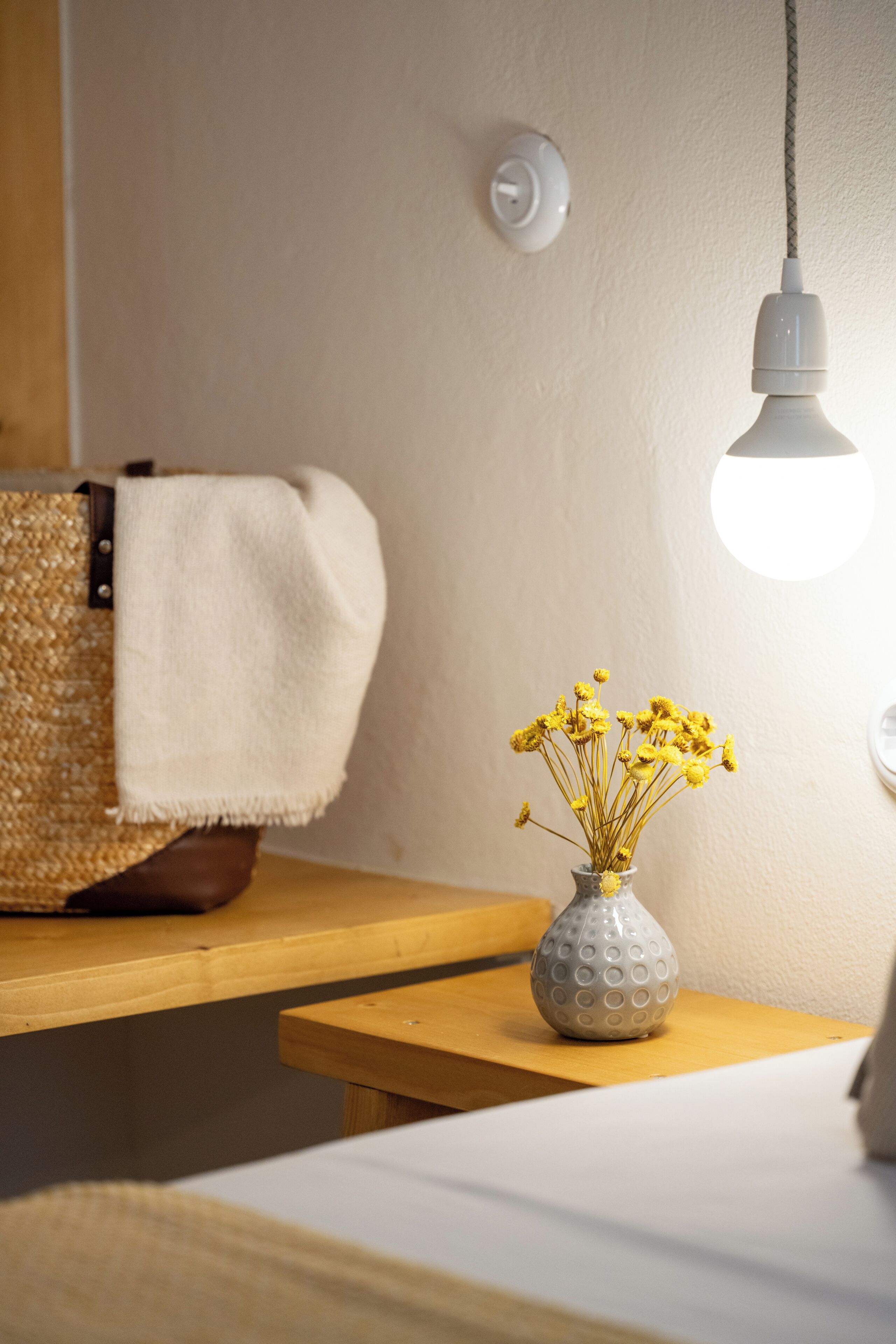 Una mesa de madera con una cesta tejida y un florero de flores amarillas.