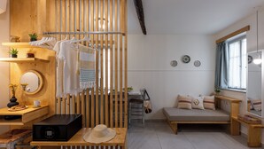 A cozy room with a wooden bench, a small table with a basket, a hanging chair, and a sofa with cushions. - Capella Skiathos Residences (Skiathos)