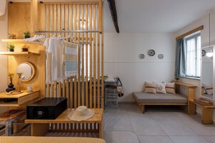 Una habitación acogedora con un banco de madera, una mesita con una cesta, una silla colgante y un sofá con cojines.