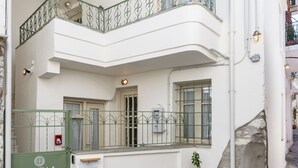 A two-story building with a balcony, a green gate, and a potted plant. - Capella Skiathos Residences (Skiathos)