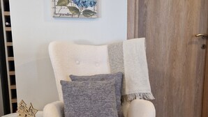 Un sillón cómodo con reposapiés, una mesita auxiliar con un adorno, y dos obras de arte en la pared.