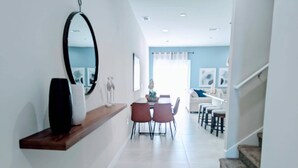 A modern interior with a dining area, a staircase, and a hallway leading to a living space. - 2024 New 3 Suites  5 min to Disney (Kissimmee)