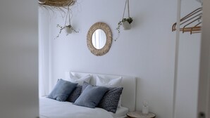 A bedroom with a bed, pillows, a round mirror, and hanging plants. - Chez Marie See I Berge I Luzern (Beckenried)