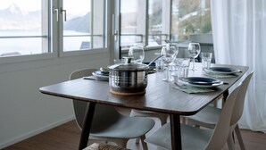 A dining table set with plates, glasses, and a pot, overlooking a scenic view. - Chez Marie See I Berge I Luzern (Beckenried)