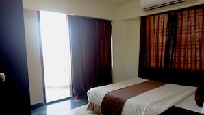 A hotel room with a bed, a window with curtains, an air conditioning unit, and a tiled floor. - Hotel Suite Sadaf (Cox's Bazar)