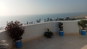 A terrace with potted plants and a view of the beach and ocean. - Hotel Suite Sadaf (Cox's Bazar)
