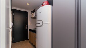 A compact kitchen with a white refrigerator, a microwave, and wooden cabinets. - Vossa Bossa Moema ON (São Paulo)