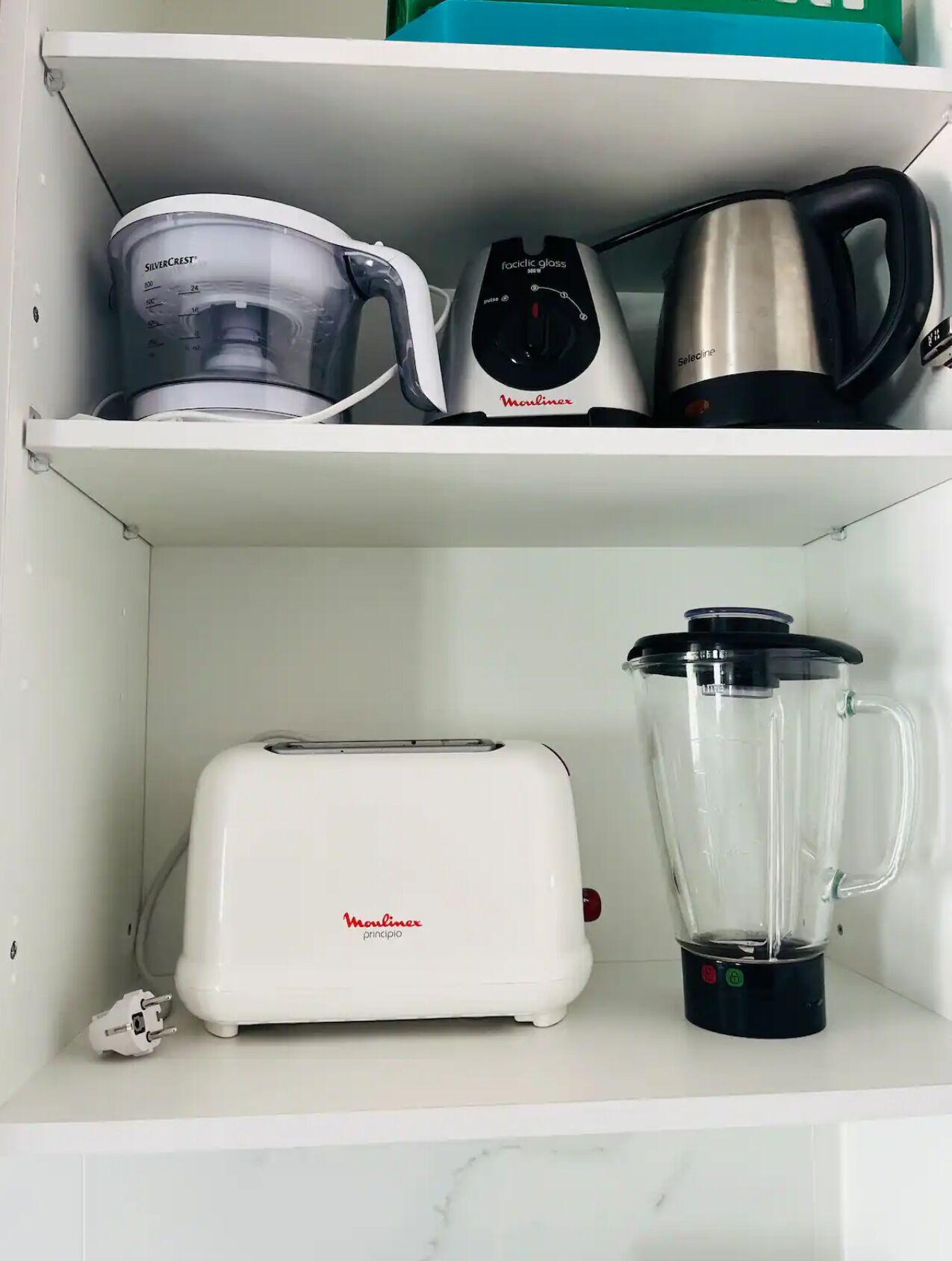 Une étagère de cuisine avec un grille-pain, un mixeur, un verre doseur et une bouilloire.