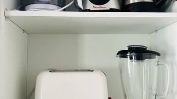 Une étagère de cuisine avec un grille-pain, un mixeur, un verre doseur et une bouilloire.