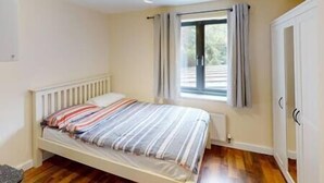 A bedroom with a bed, a window with curtains, and a door. - Lovely two bed flat with free parking (Nottingham)