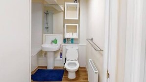 A small, narrow bathroom with a white sink, toilet, and a blue bath mat. - Lovely two bed flat with free parking (Nottingham)
