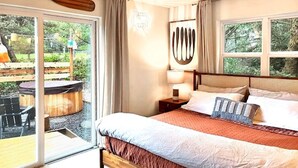 Una camera da letto con un letto grande, una testata in legno, un comodino, una lampada e vista sull'esterno tramite una porta scorrevole in vetro.