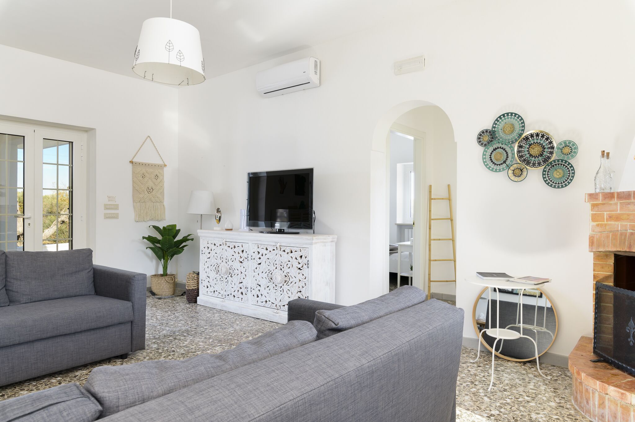 Una sala de estar moderna con sofás grises, un mueble blanco para entretenimiento y una chimenea.
