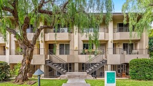 Un edificio de apartamentos de varios pisos con una escalera central, balcones y un letrero verde que indica los números de las habitaciones.