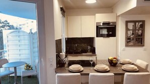 A compact kitchen with a dining area, a refrigerator, a microwave, and a dining table set for four. - Charming apartment with terrace, near Paris (Courbevoie)