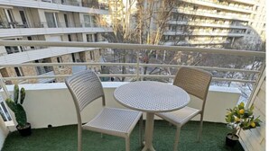 A balcony with two chairs and a table, surrounded by potted plants. - Charming apartment with terrace, near Paris (Courbevoie)