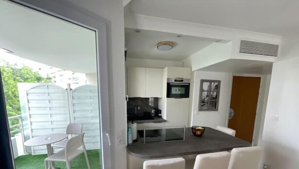 A compact kitchen with a dining area, a small refrigerator, and a microwave. - Charming apartment with terrace, near Paris (Courbevoie)